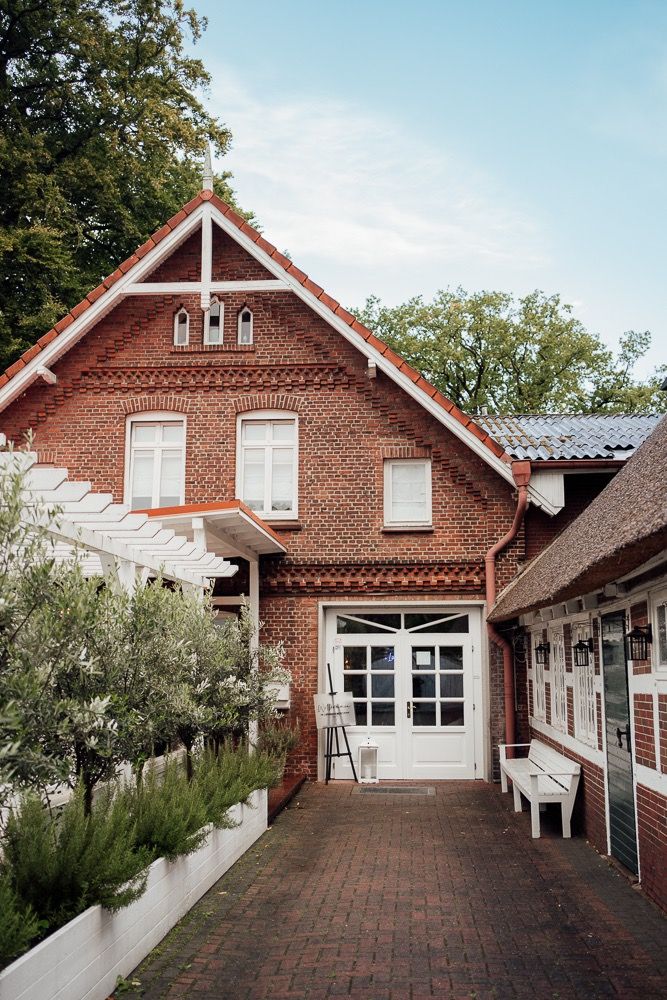 Red brick farmhouse style venue with white trim and multiple connecting buildings creates a charming courtyard setting.