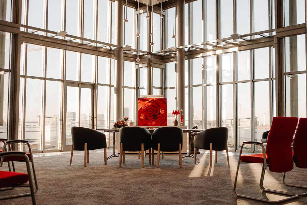 Modern meeting room with floor-to-ceiling windows, black chairs, and red accents in a contemporary office space.