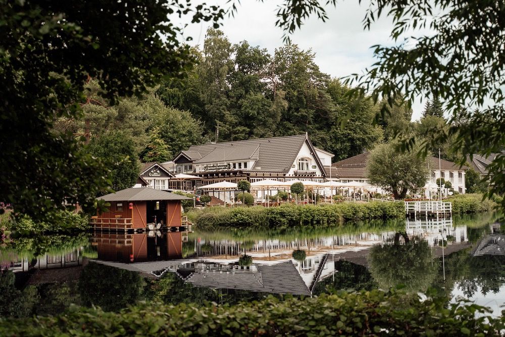 A scenic waterfront view showing multiple lakeside homes and boat docks nestled among trees along the shoreline.