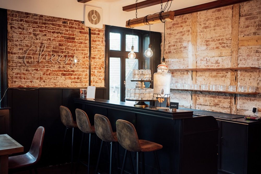 Modern restaurant interior with exposed brick walls, pendant lighting, and wooden tables and chairs creates an industrial chic ambiance.