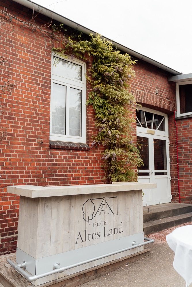 Red brick building entrance with white stone benches and climbing vines along the wall.