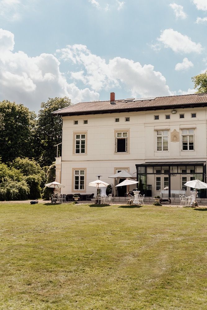 White country house with outdoor patio seating and large grassy lawn area viewed from multiple angles.