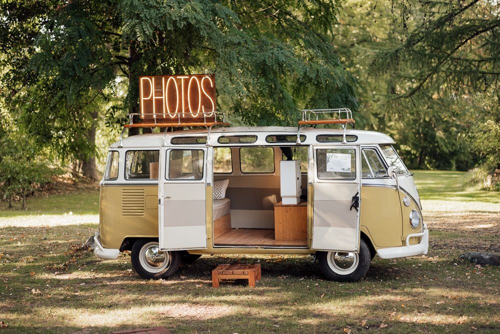 Vintage cream-colored camper van parked in a rustic outdoor setting with trees in the background.