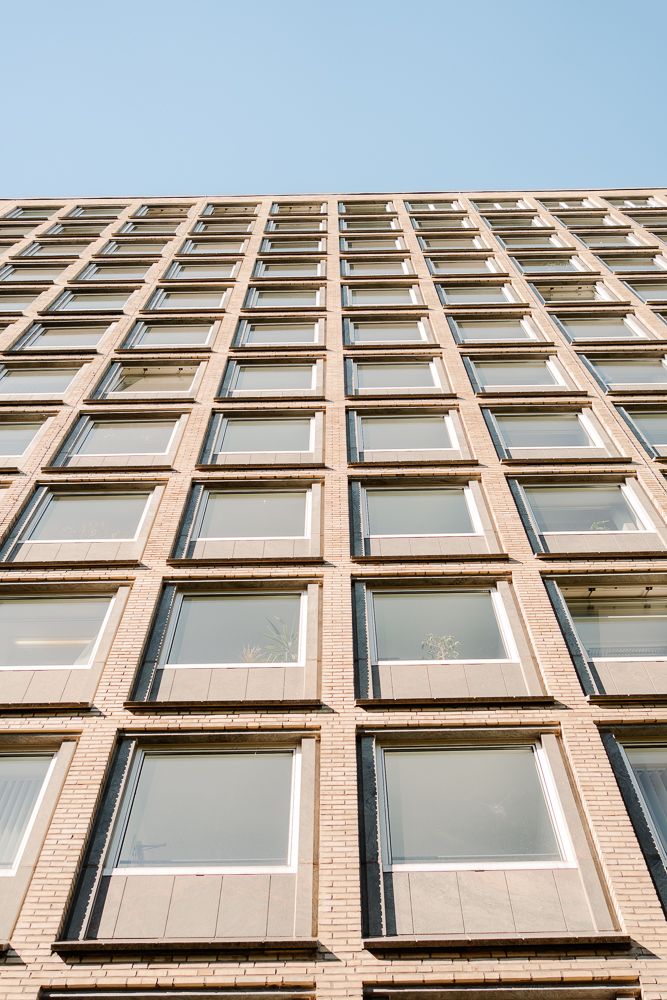 Modern office building exterior with repetitive geometric pattern of windows and tan colored concrete facade.