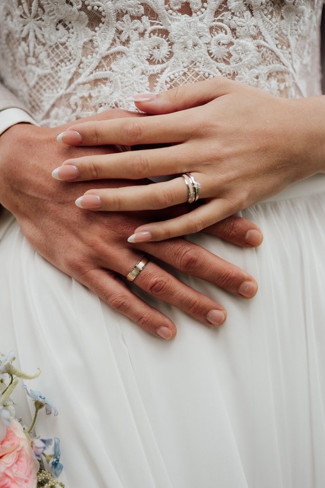 A sequence of hands wearing wedding rings shown against a white floral background in a romantic progression.