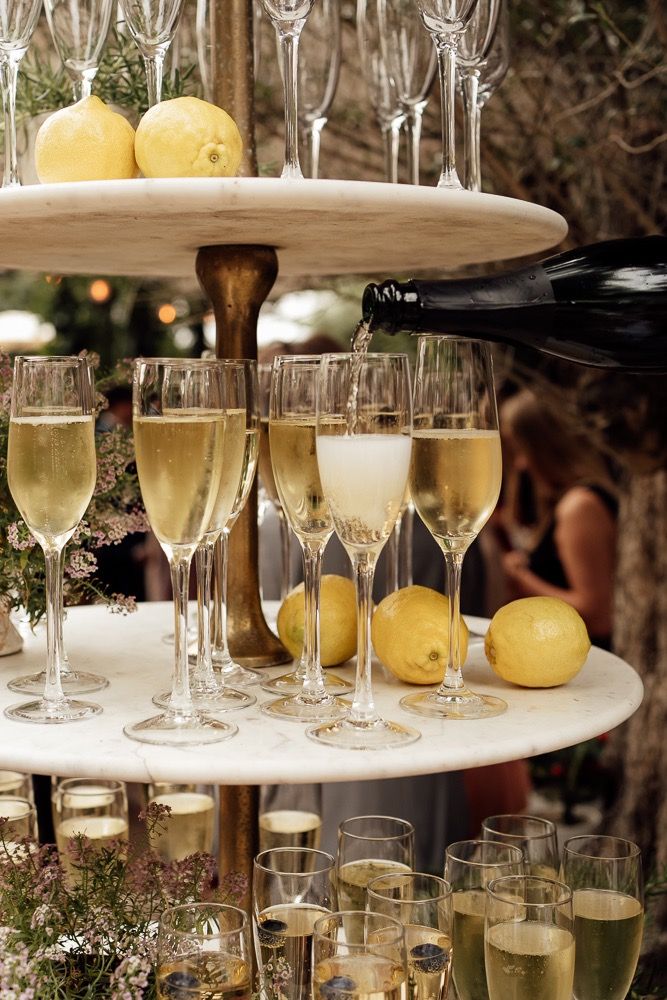 Elegant tiered display of champagne flutes and fresh lemons on marble stands at an upscale event.