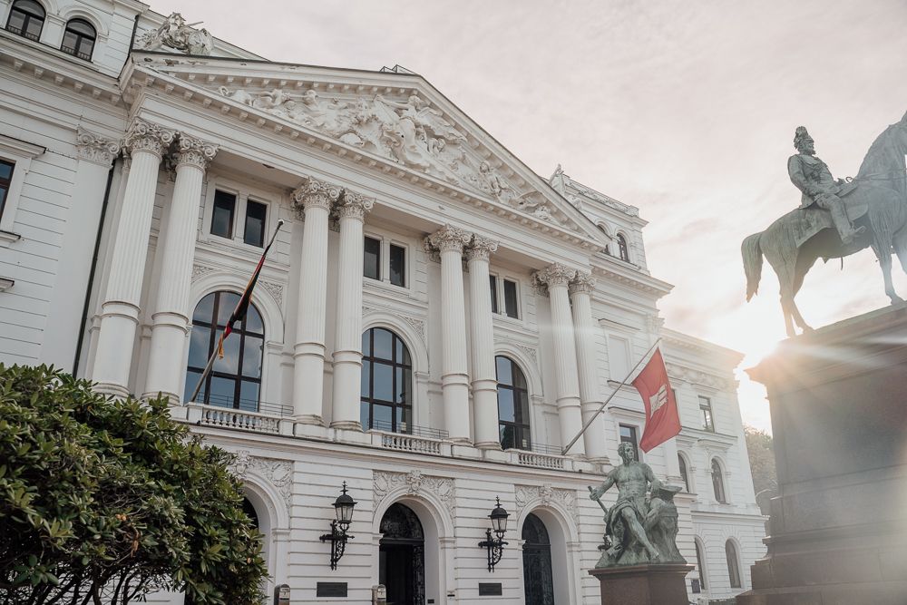 Ornate white neoclassical government building facade with columns and decorative sculptures in Vienna, Austria.