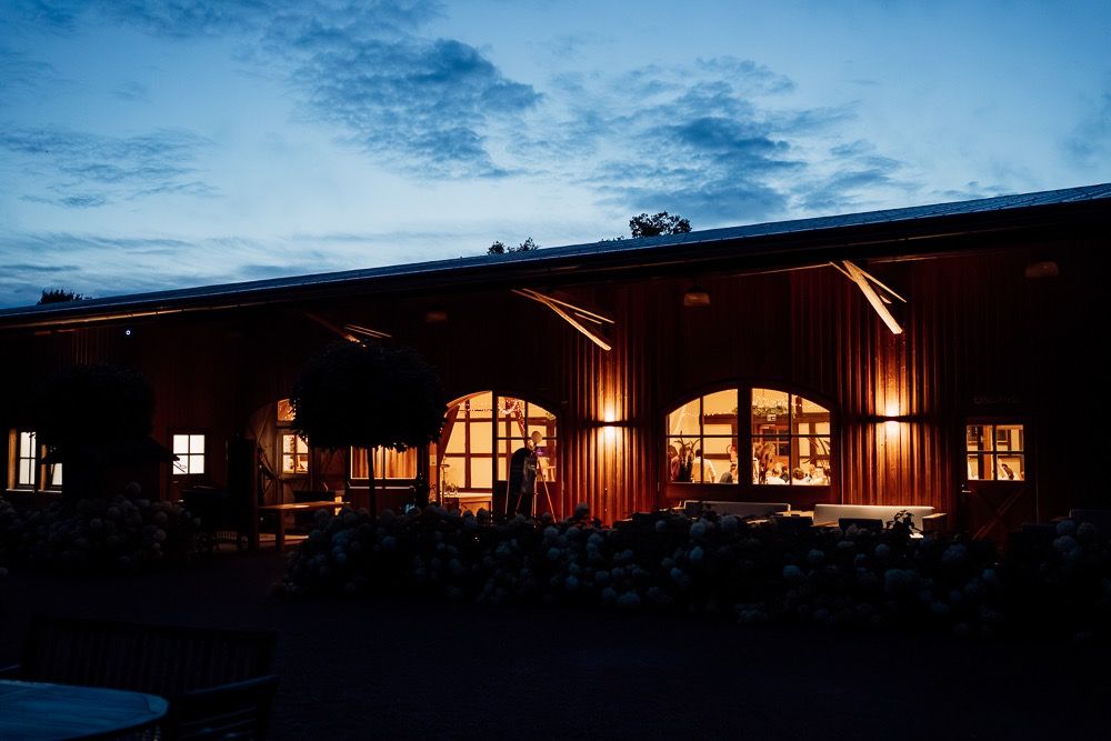 Glowing windows illuminate a rustic wooden lodge exterior against a dusky blue evening sky.