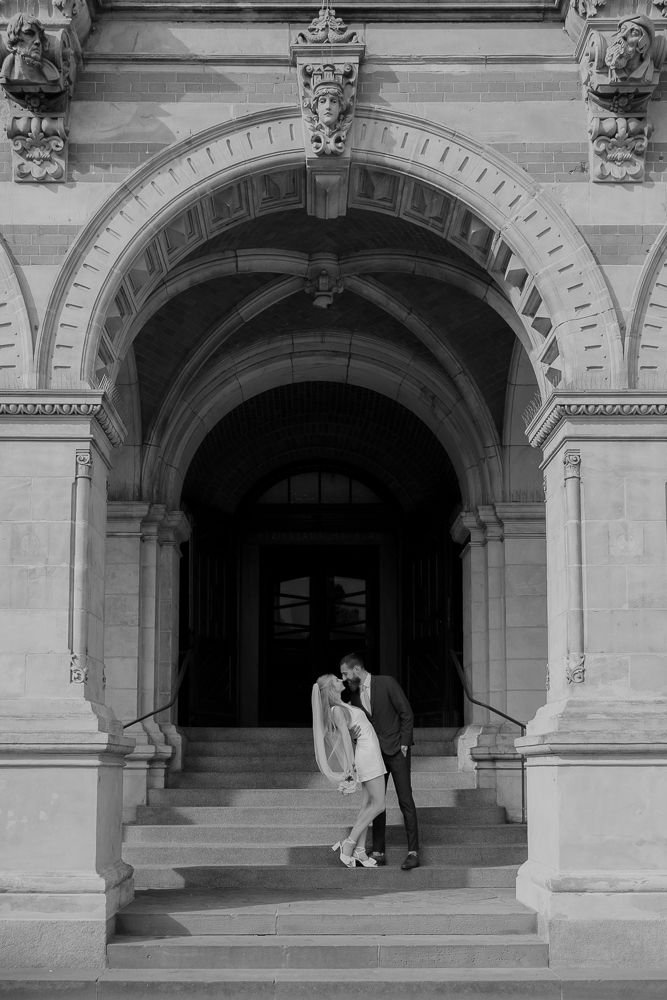 A sequence of black and white photographs showing a figure moving through an arched stone doorway entrance.