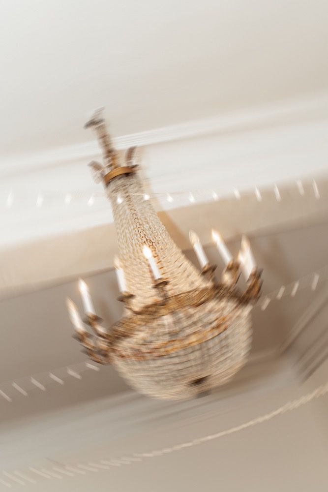 A blurred motion sequence of a crystal chandelier spinning shows movement across multiple frames in warm lighting.