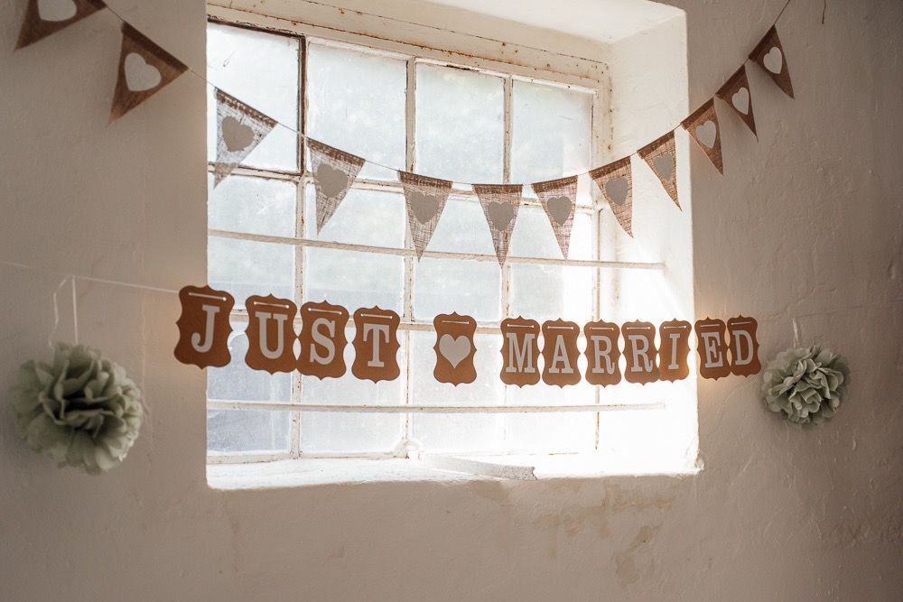 Rustic wedding venue decorated with bunting banners and window light creating a warm, romantic atmosphere.
