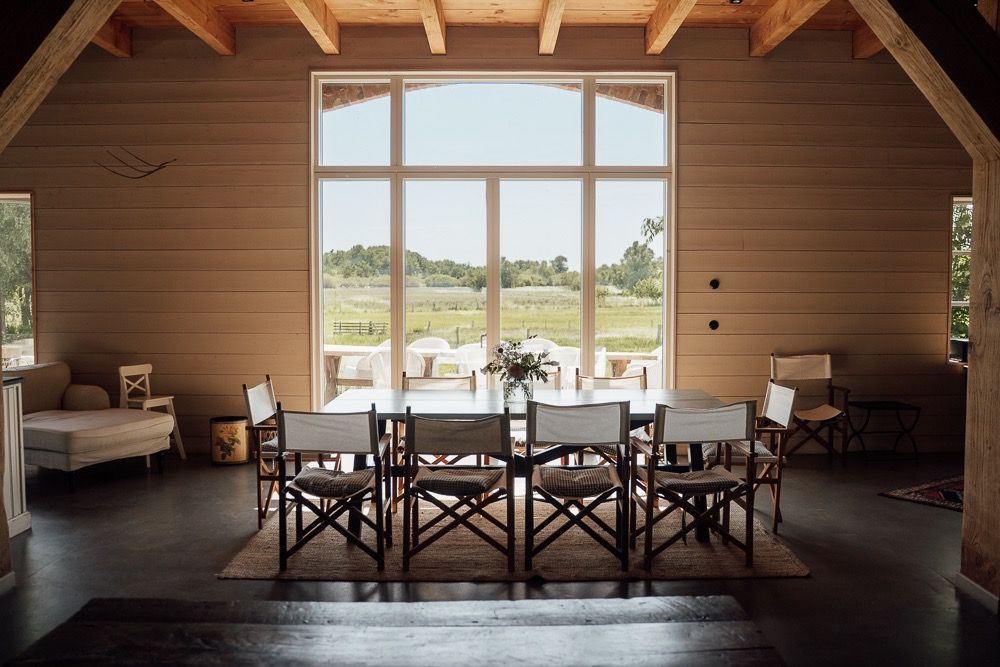 Modern wooden dining room with exposed beams and large windows overlooking scenic mountain landscape.