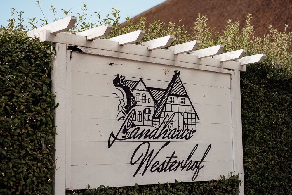 A series of white walls with black graffiti artwork showing a bicycle and text design in an outdoor setting.