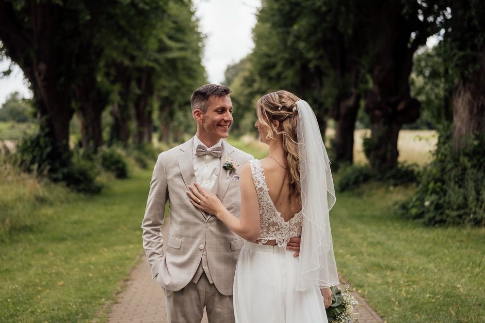 A couple shares an intimate moment in a beautiful outdoor setting with lush greenery and trees.