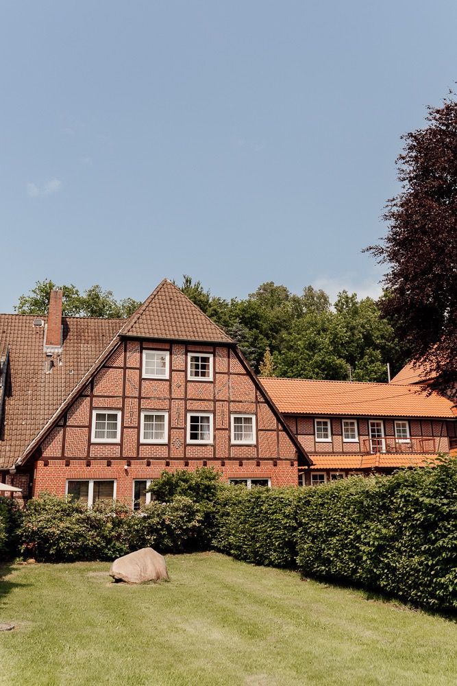 A panoramic view of traditional red brick German houses with tiled roofs along a grassy lawn in a residential neighborhood.