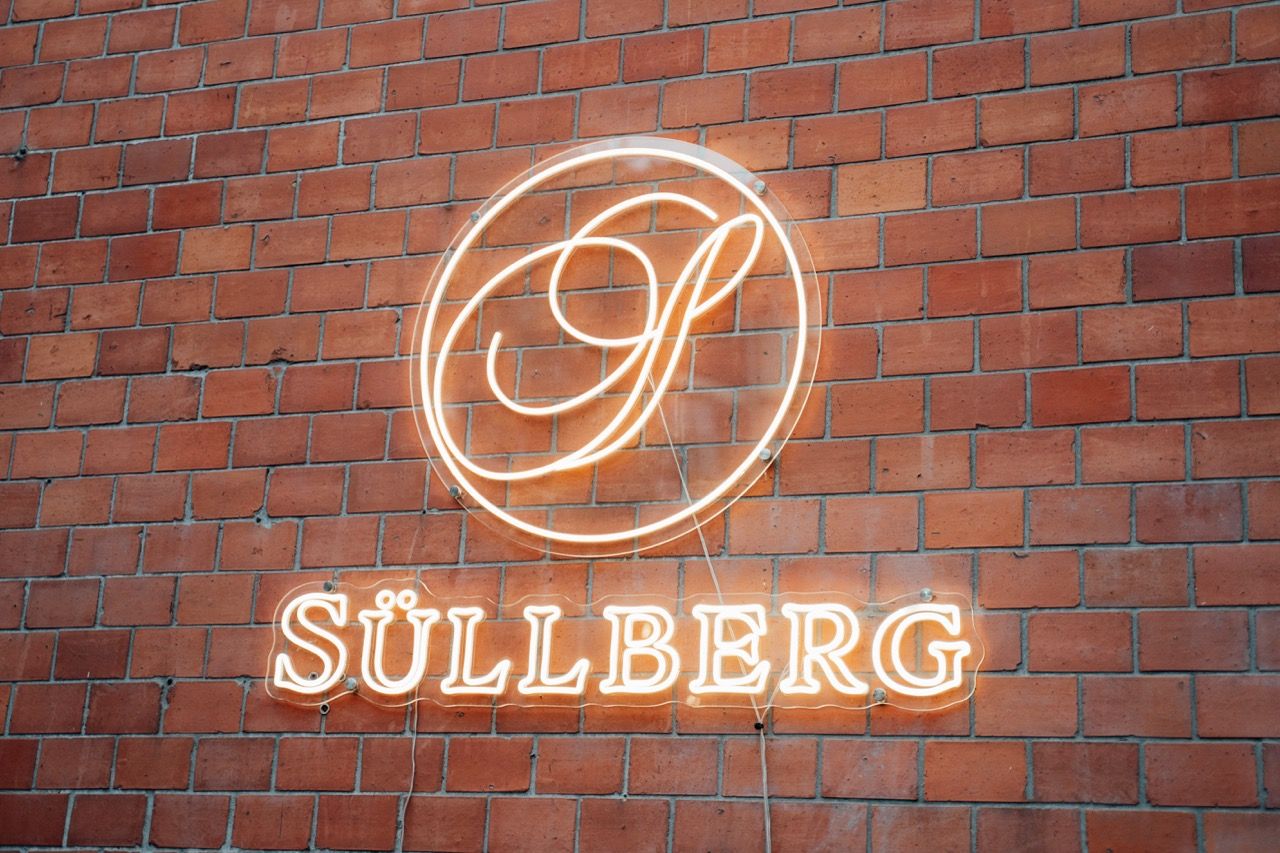 Glowing neon sign of Süllberg restaurant logo on a red brick wall in Hamburg.