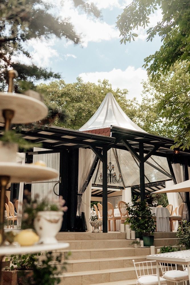 Elegant outdoor wedding venue with white canopy tents and black pergola structures creating a romantic garden atmosphere.