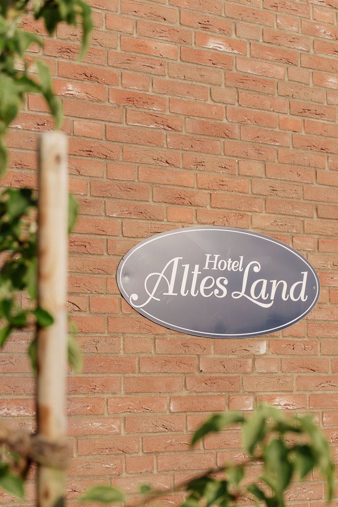 Hotel sign mounted on red brick wall with decorative text and elegant oval shape design.