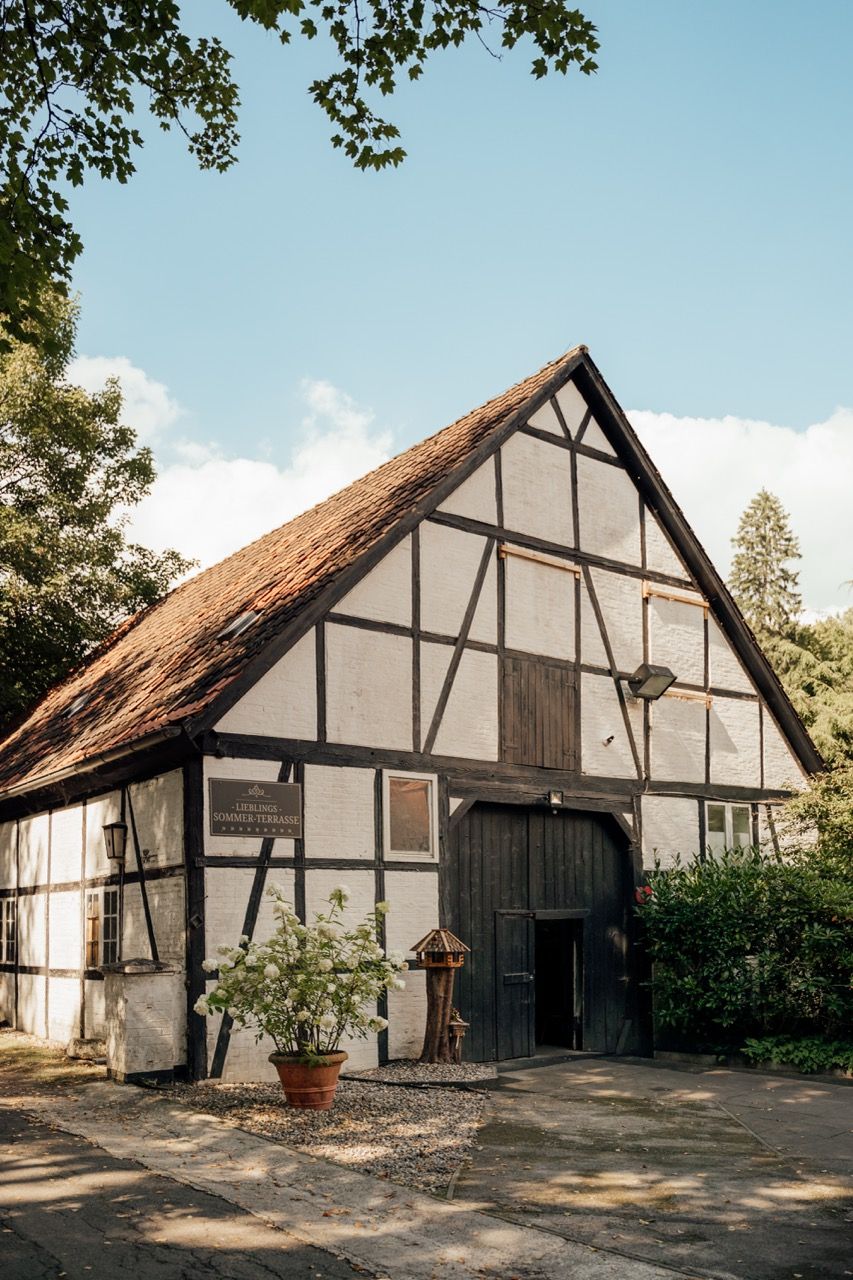 Historic half-timbered barn with white walls and dark wooden beams under a blue sky in Germany.