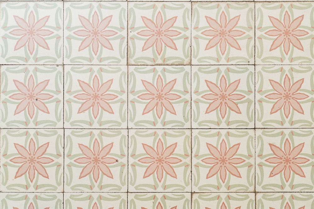 Vintage floral wallpaper pattern featuring pink geometric flowers and pale green background in repeating tiles.