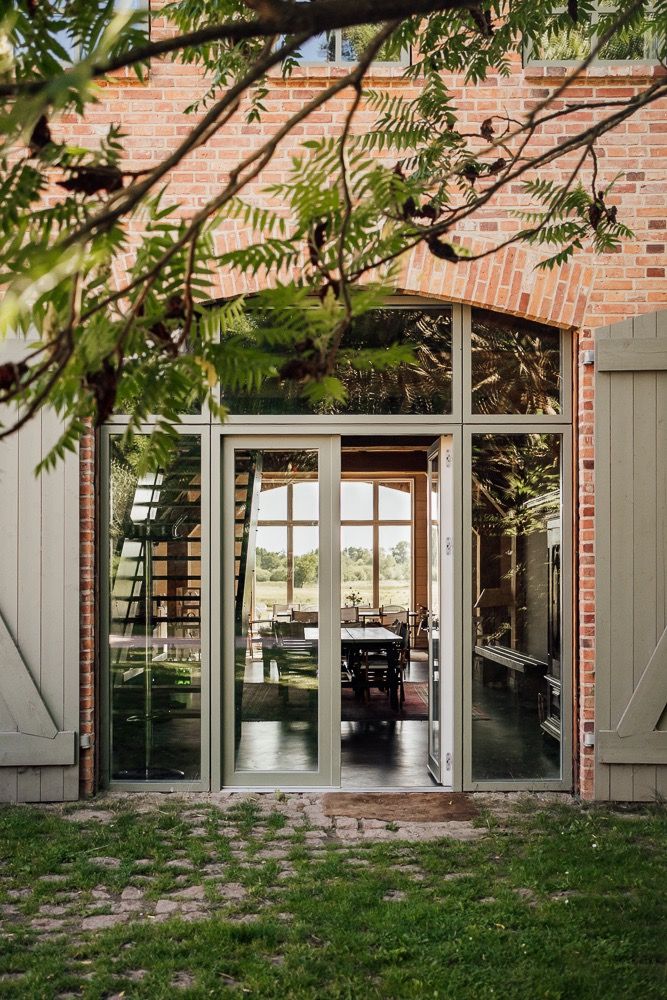 Brick building exterior with gray shuttered windows and green foliage framing the architectural details.
