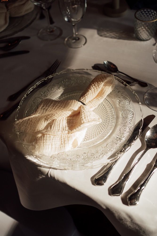 White lace doily placemats arranged on a dining table with silverware and wine glasses in a formal setting.