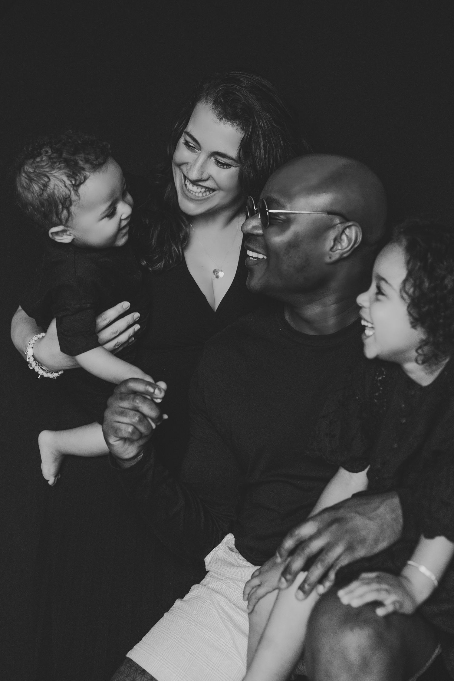 Black and white portrait of joyful interracial family of four sharing a loving moment.
