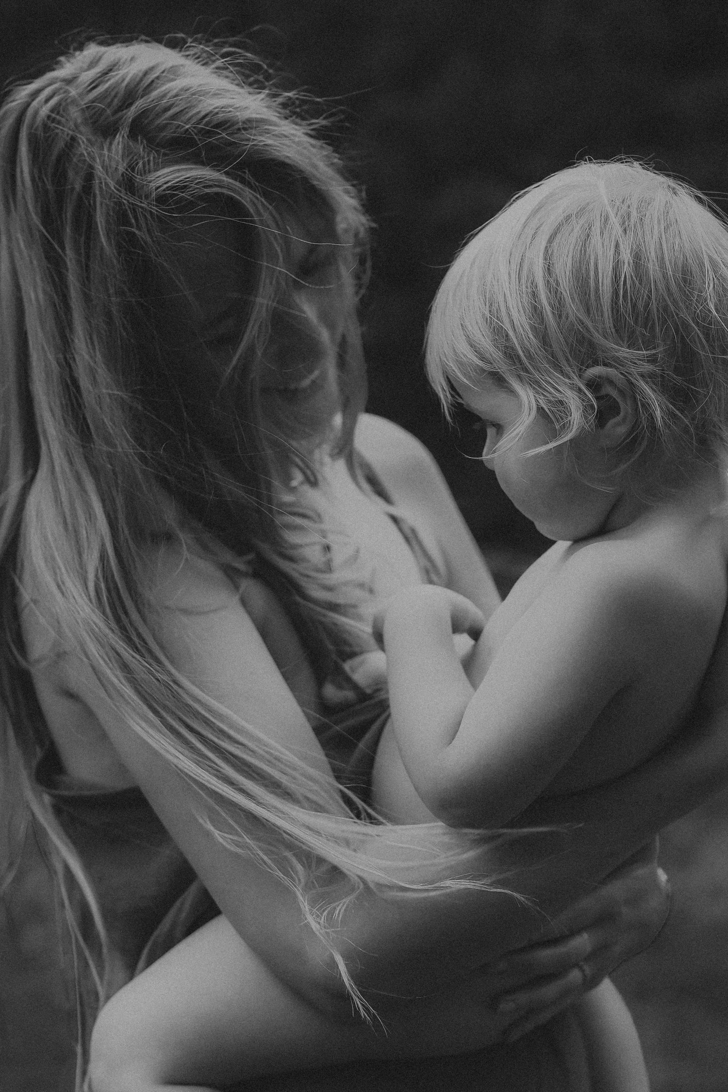 Black and white photo of mother tenderly holding young child.