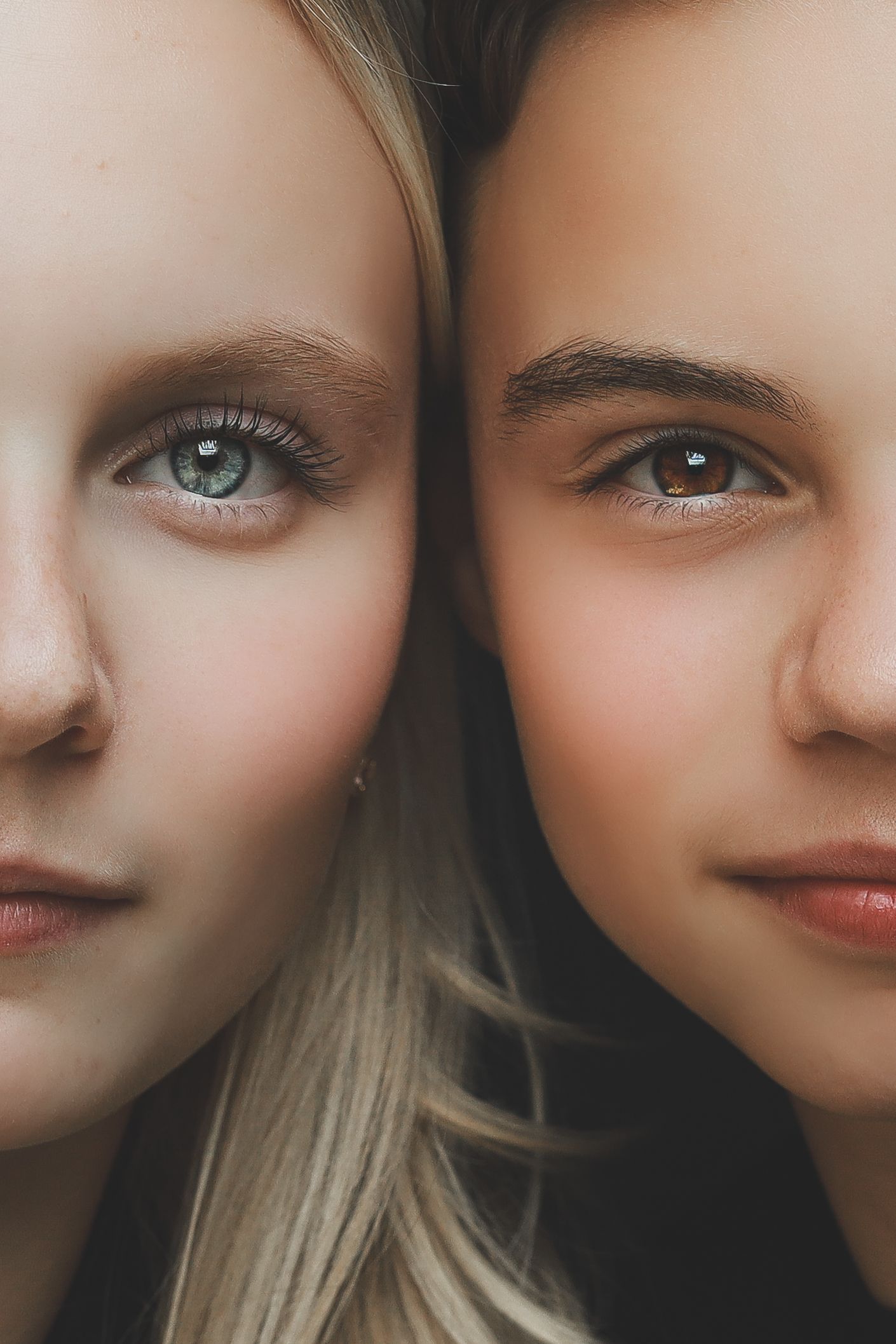 Close-up portrait of two young women with contrasting blonde and brunette hair.
