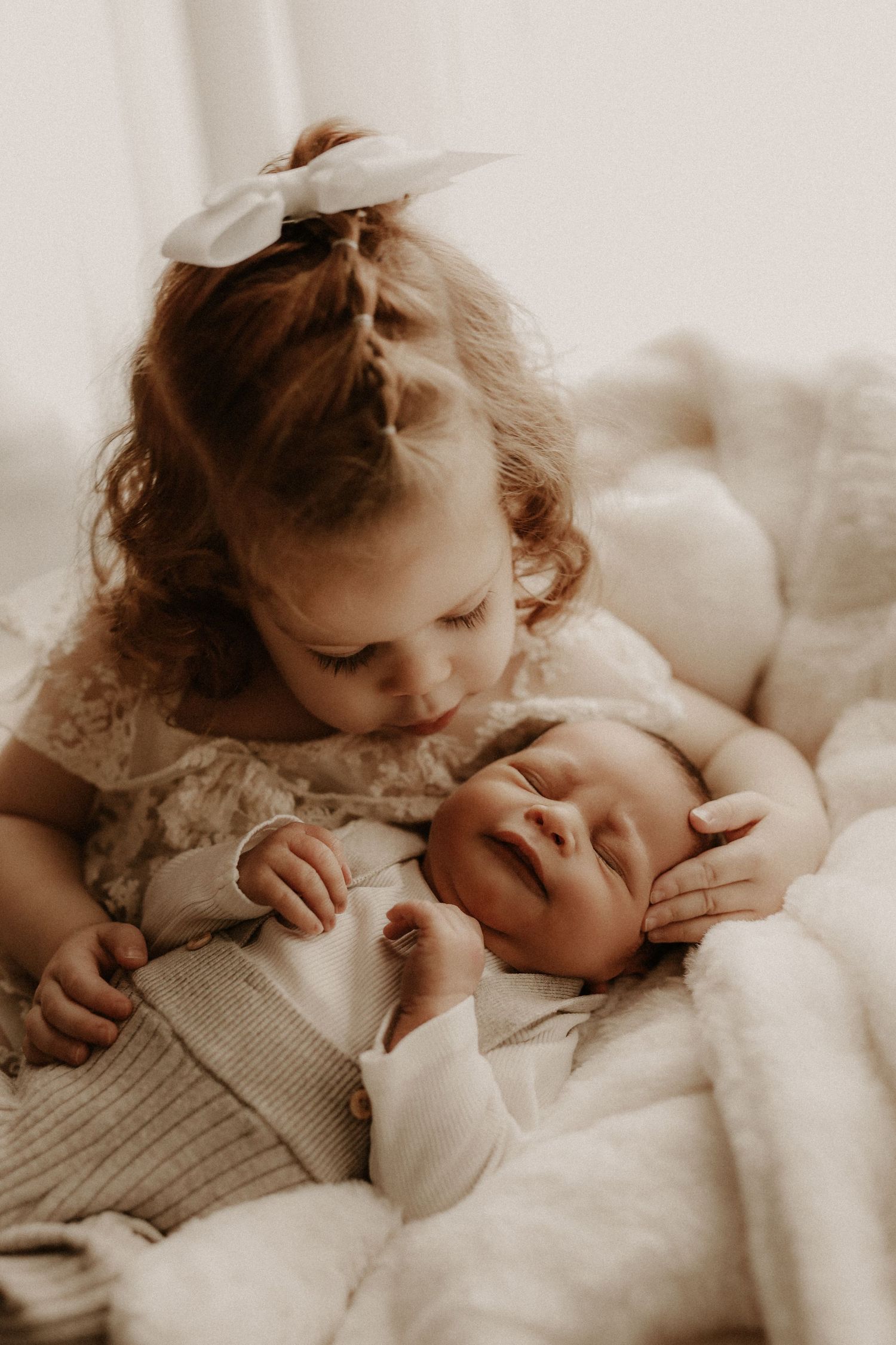 Pasgeboren baby in de armen van het zusje, gefotografeerd door een newbornfotograaf in Zwolle.