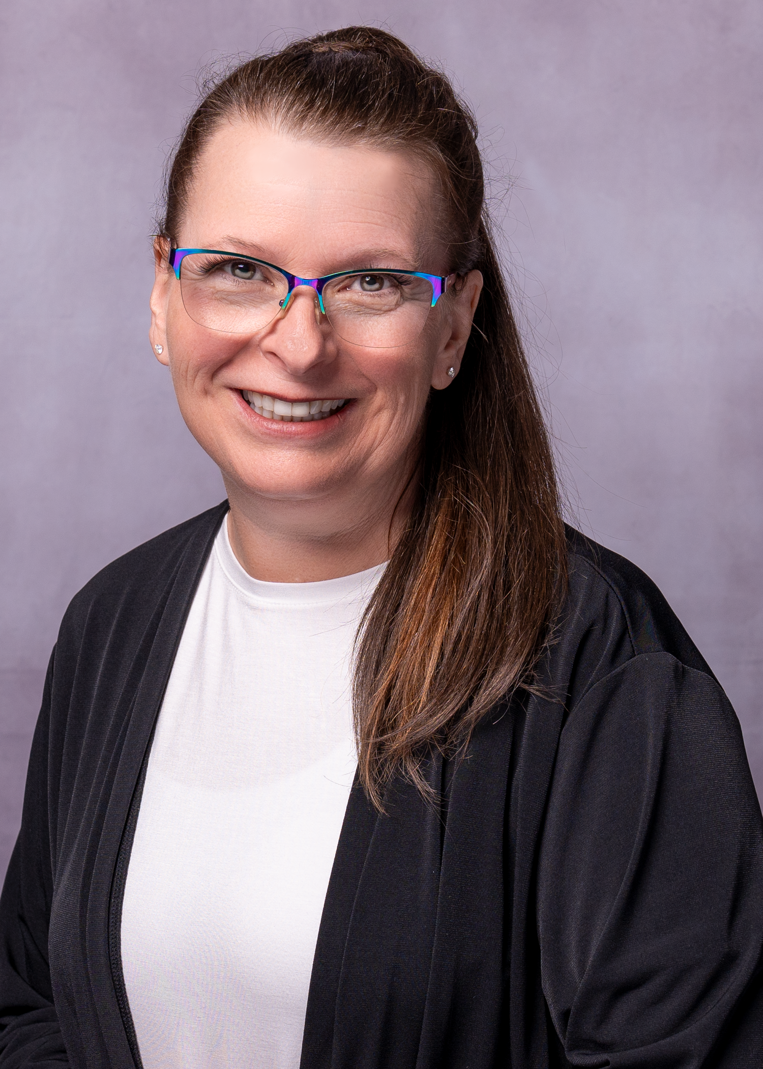 Professional headshot of a smiling woman with glasses, dark hair, wearing a white shirt and black cardigan.
