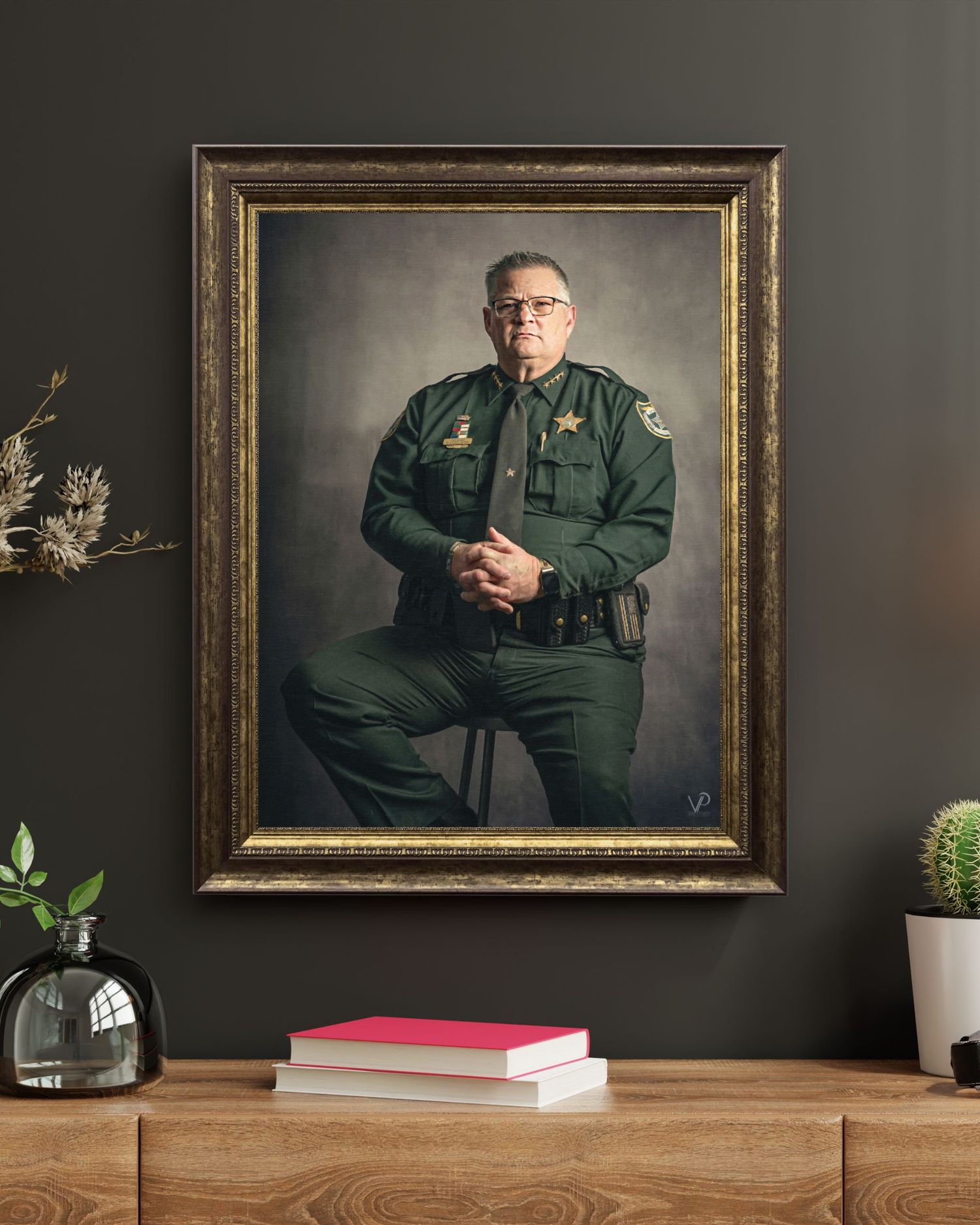 Framed portrait of a sheriff in green uniform displayed on a dark wall above a wooden console table.