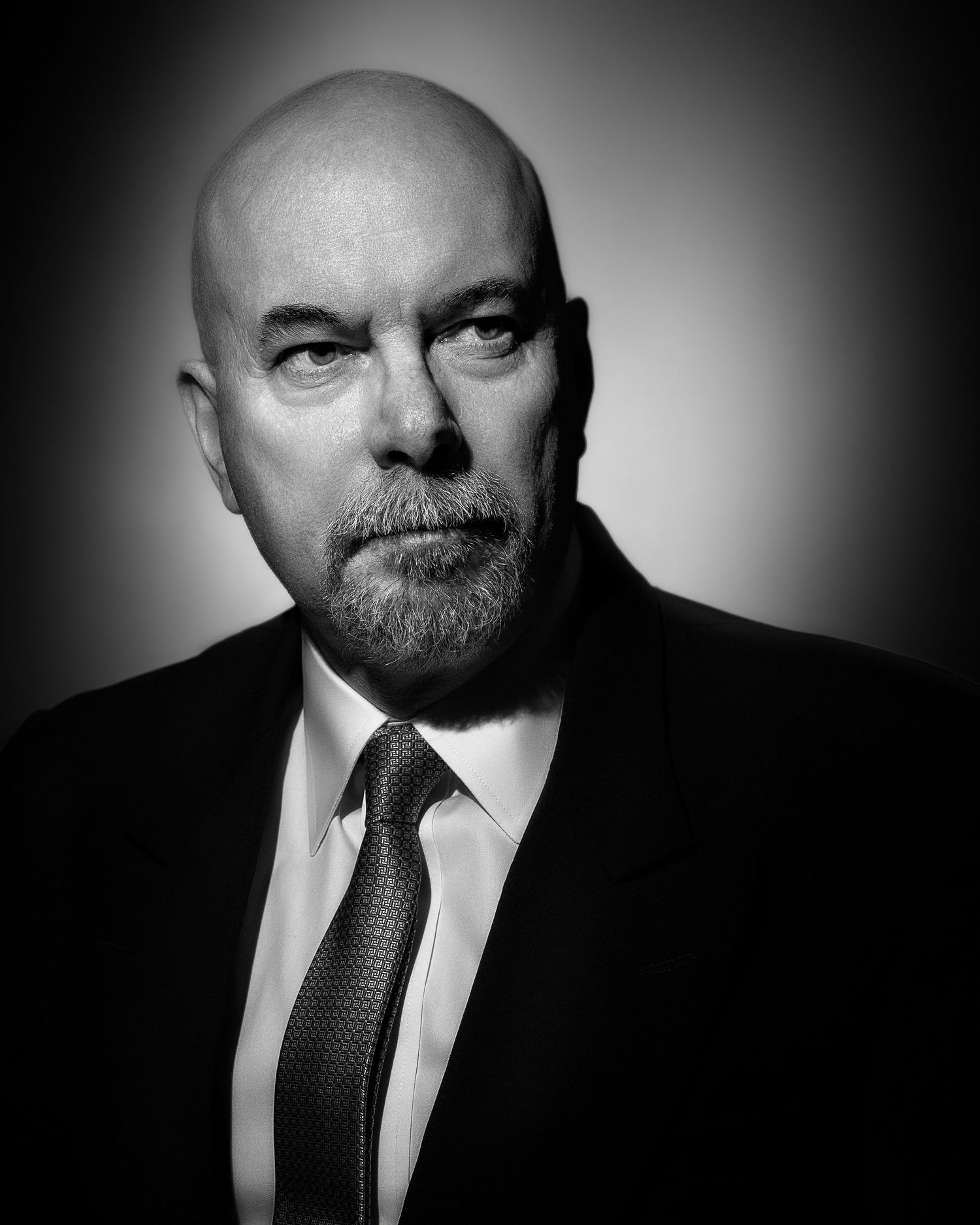 Black and white portrait of a bald man with a beard wearing a suit and tie.