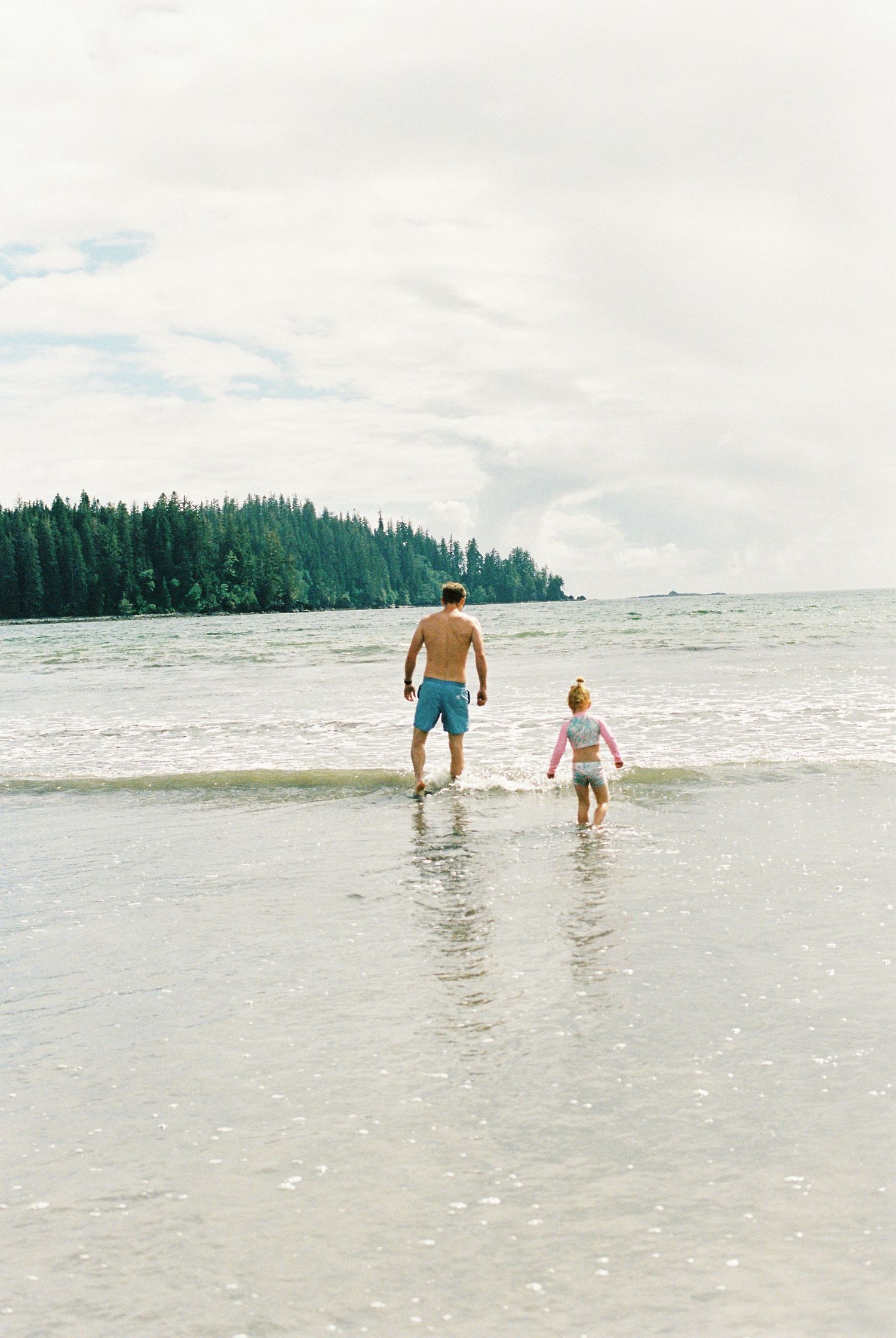 A film photo on Portra 400 of a father and daughter walking into the ocean in Bamfeild