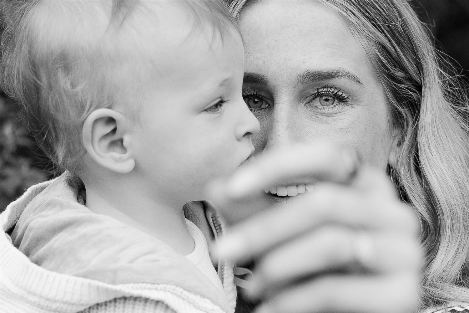 A black and white intimate portrait showing a tender moment between parent and child in soft natural lighting.