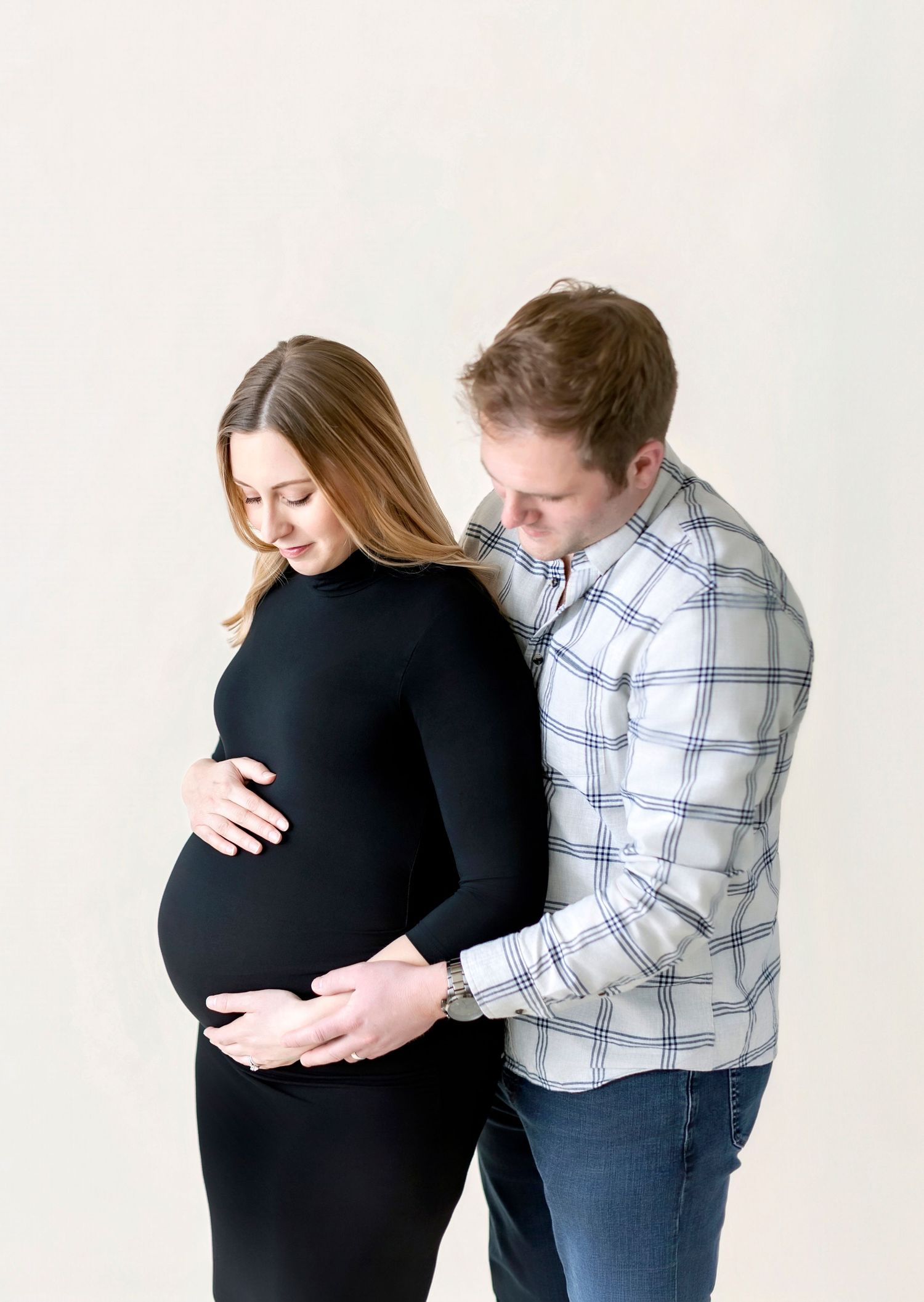 Couple sharing a tender moment during a maternity photo shoot, man gently holding pregnant woman's belly.