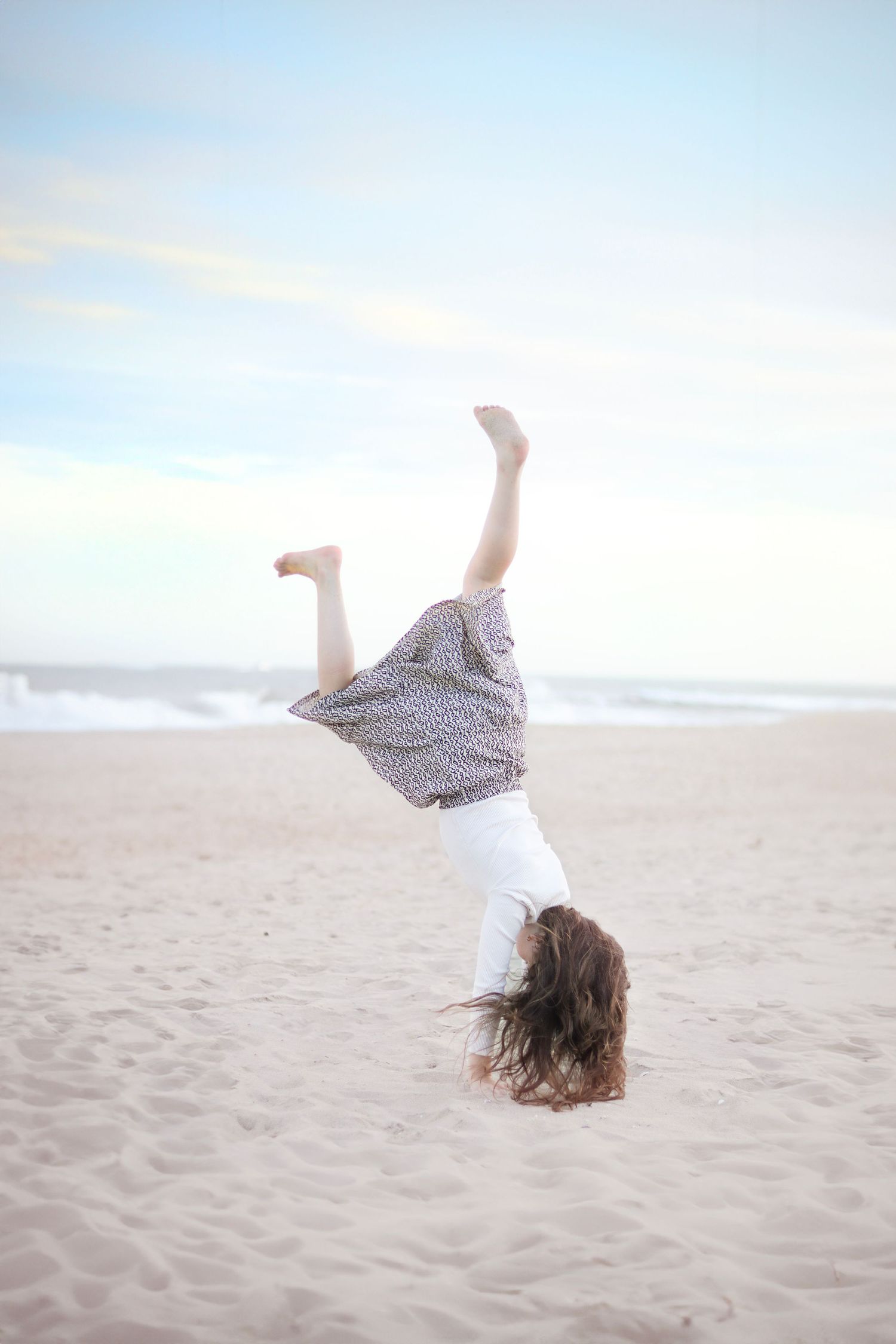candid photo of a girl doing cartwheels on the sand at the Jersey Shore