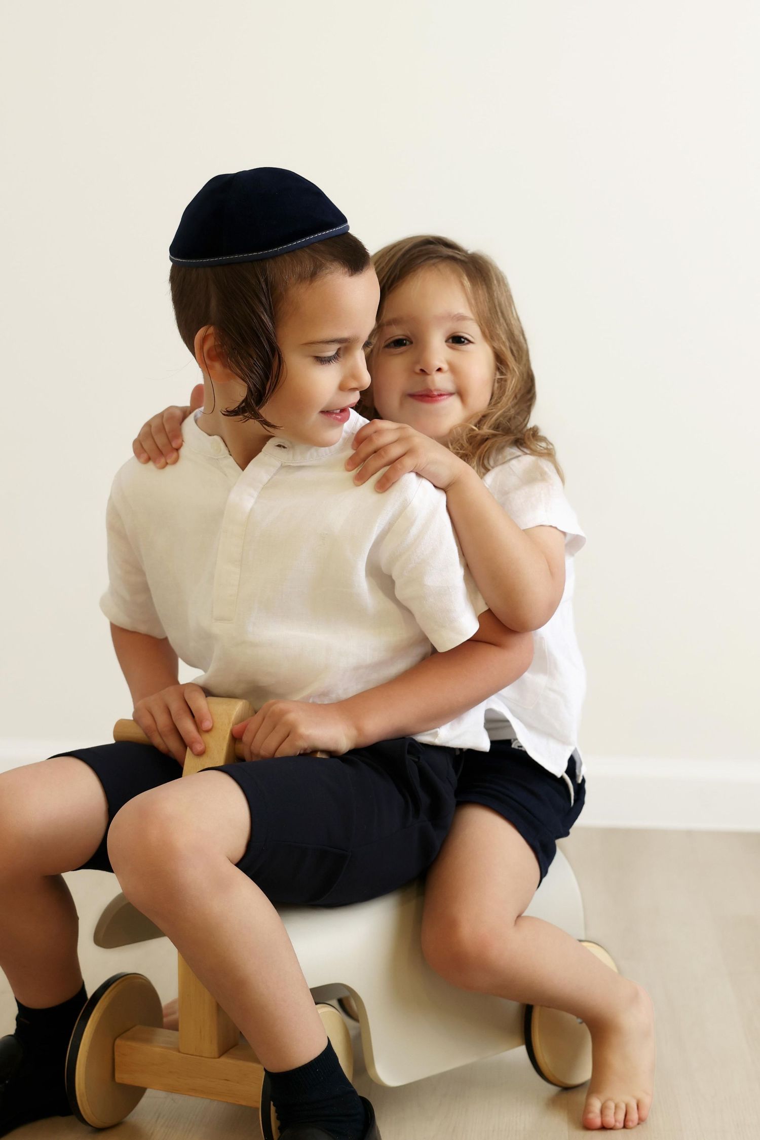 Studio portrait of brothers having fun together on a wooden riding toy