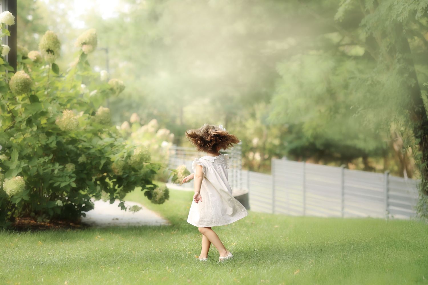 candid fine art photo of a young girl spinning in the grass with her hair flying in the wind