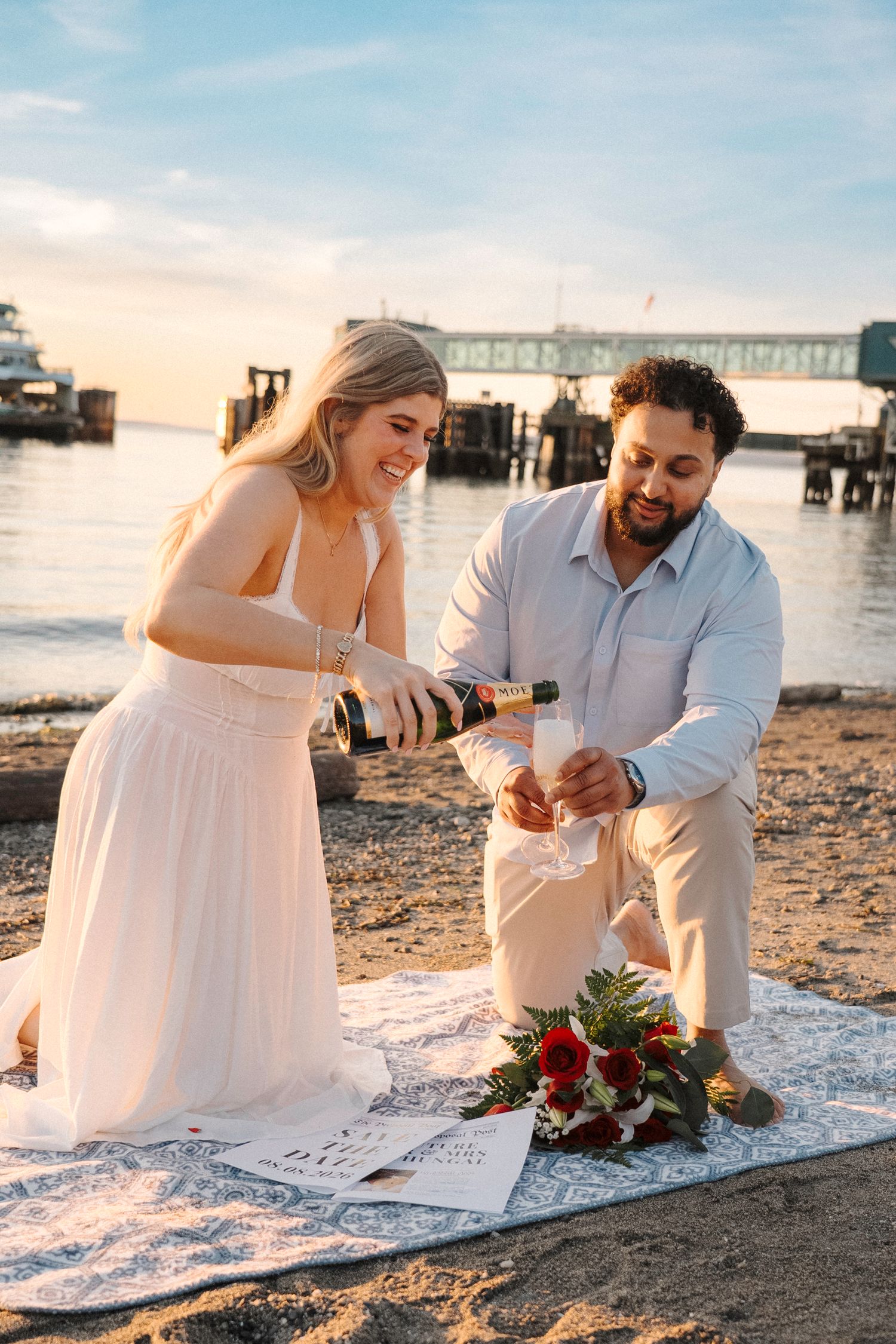 A couple sitting on a beach blanket at sunset enjoying an intimate beach picnic celebration.