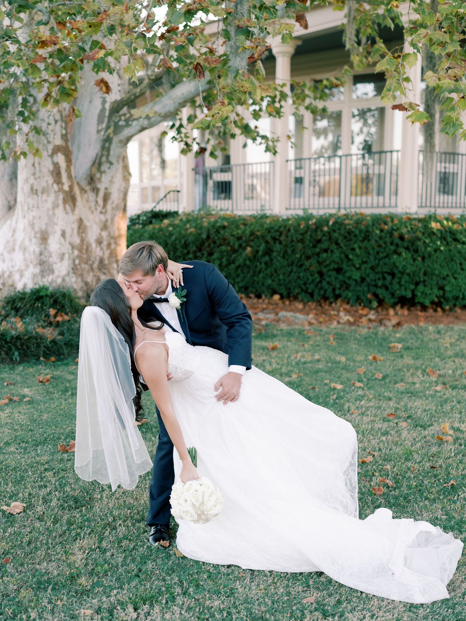 Romantic wedding couple shares intimate moments on a grassy lawn with autumn leaves scattered around.