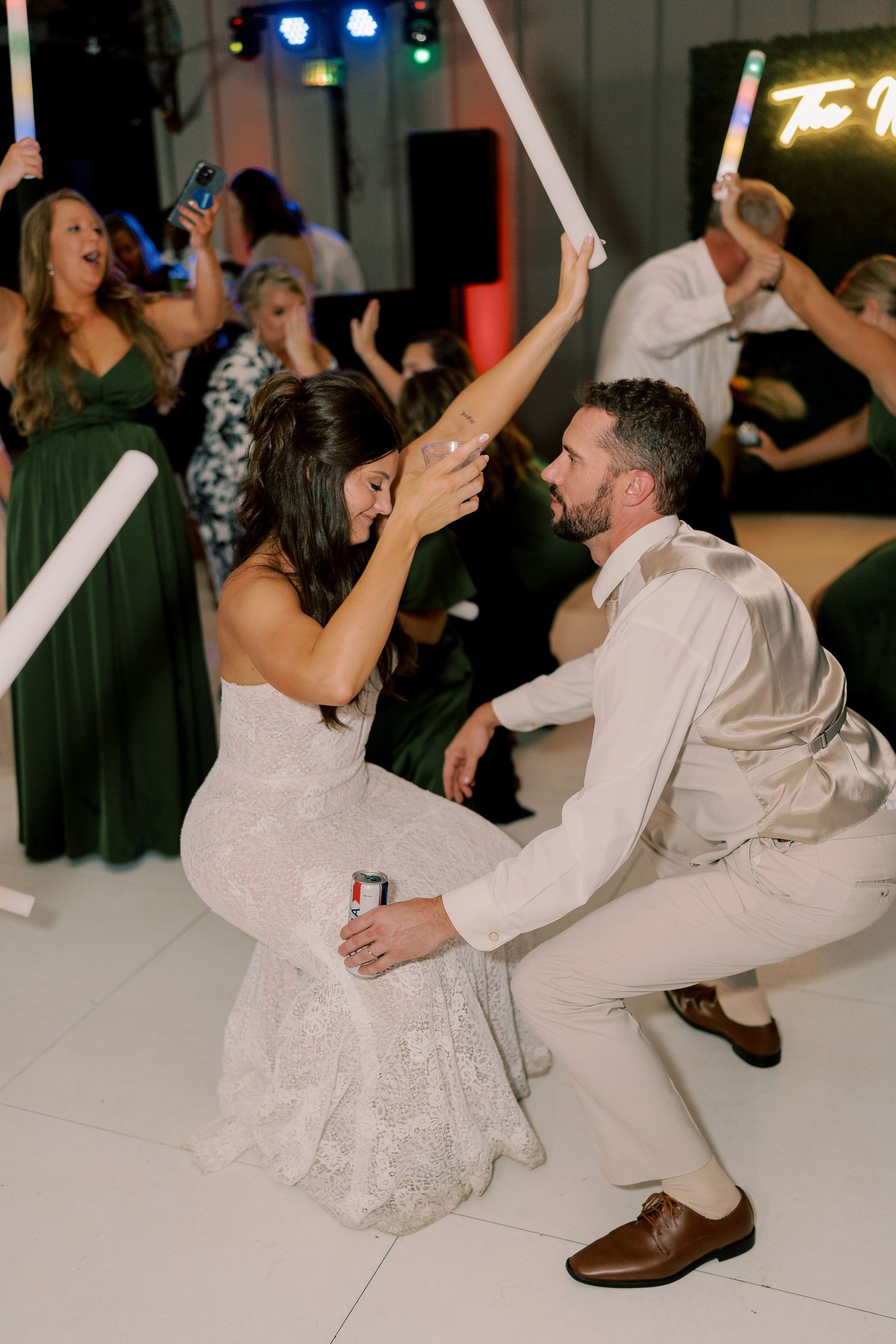 Wedding couple dancing energetically on a white dance floor at their reception celebration.