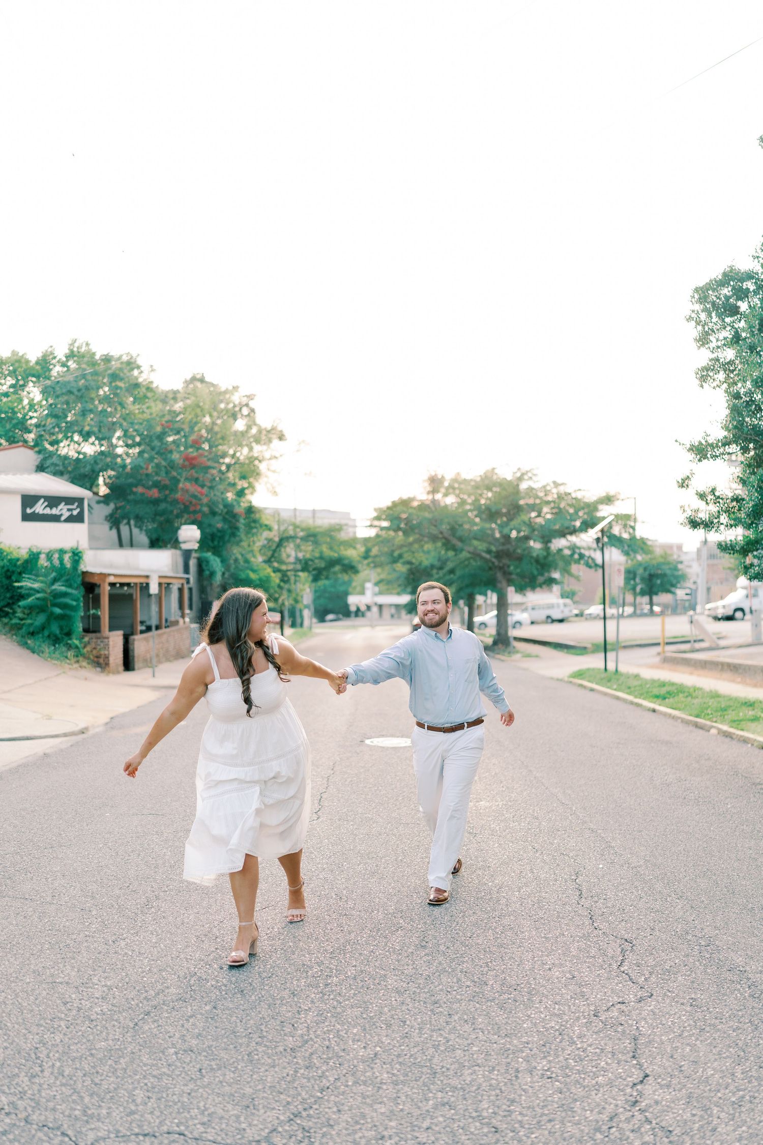 A joyful couple runs and plays together on a paved street during their photo session.