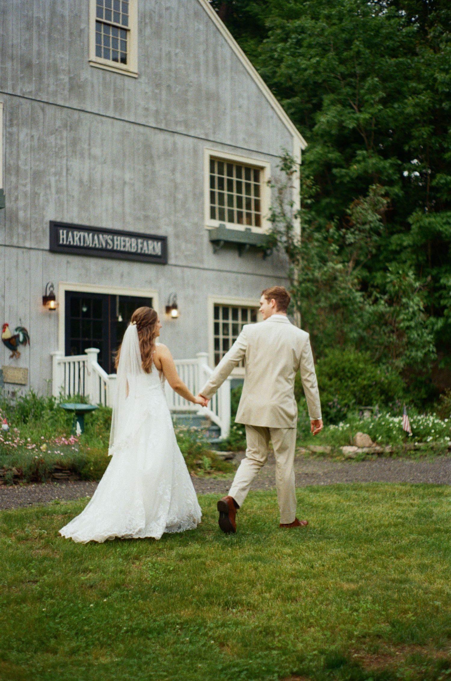 A couple walks hand in hand outside Hartman's Herb Farm building on their wedding day.