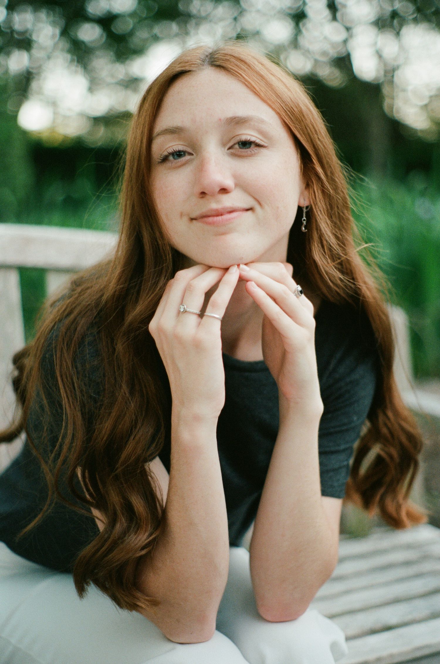 Playful portrait series showing expressions with hands framing face against blurred natural background.