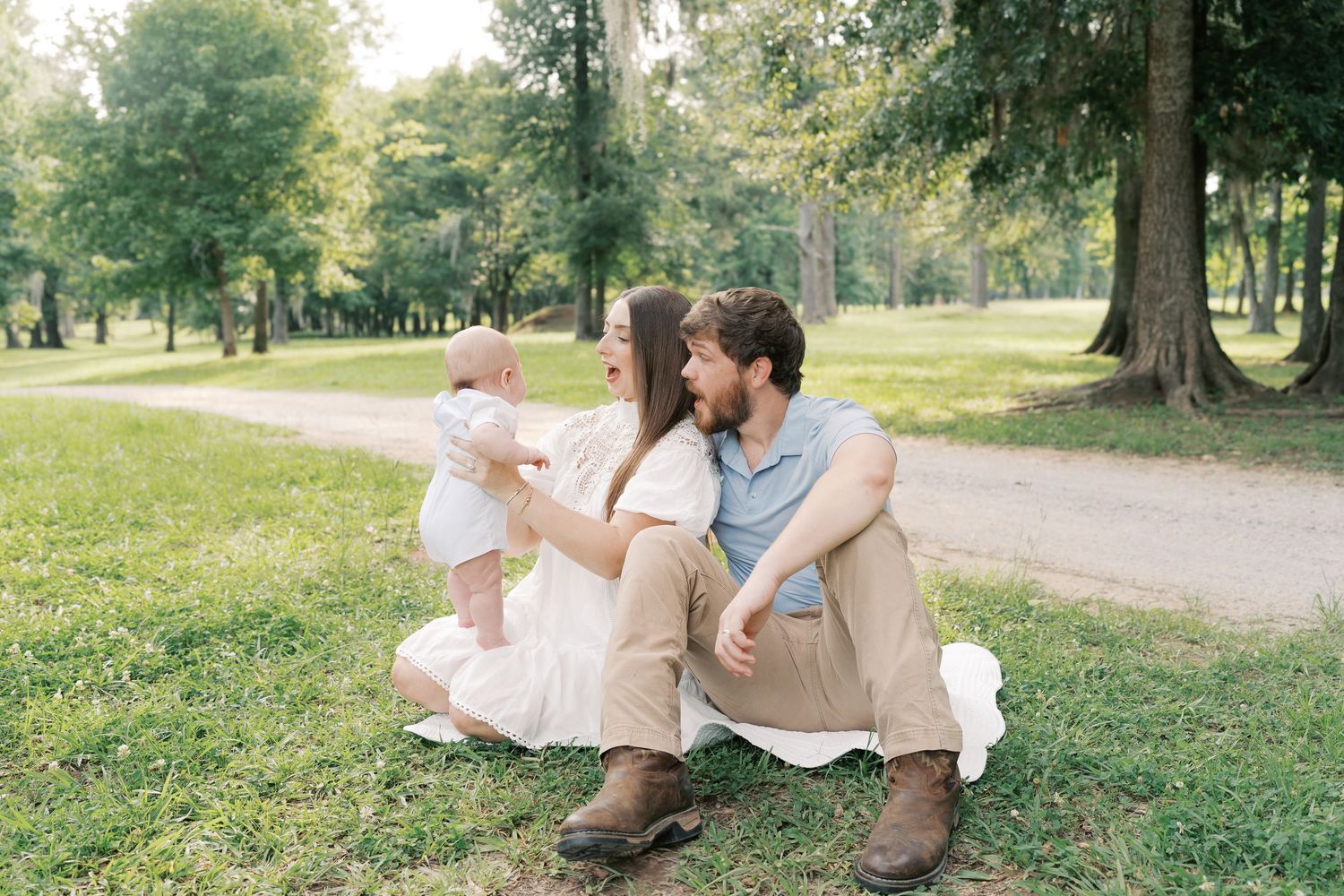 Family enjoying a relaxing afternoon together on grassy ground in a serene park setting.