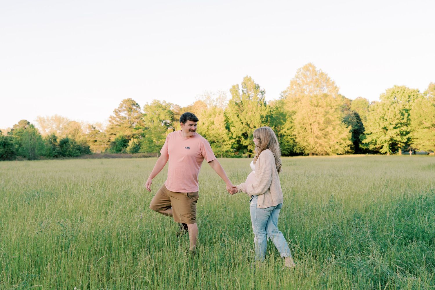 A couple shares an intimate moment in a sunlit field during golden hour.