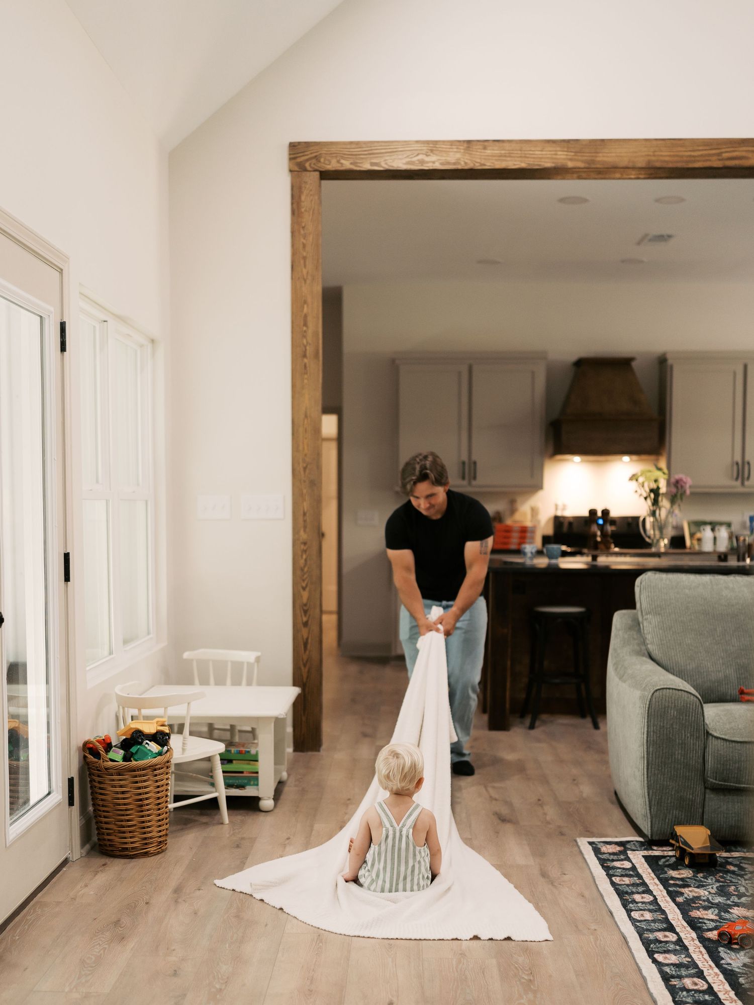 A sequence showing a white blanket fort being built in a modern living room with wood beams.
