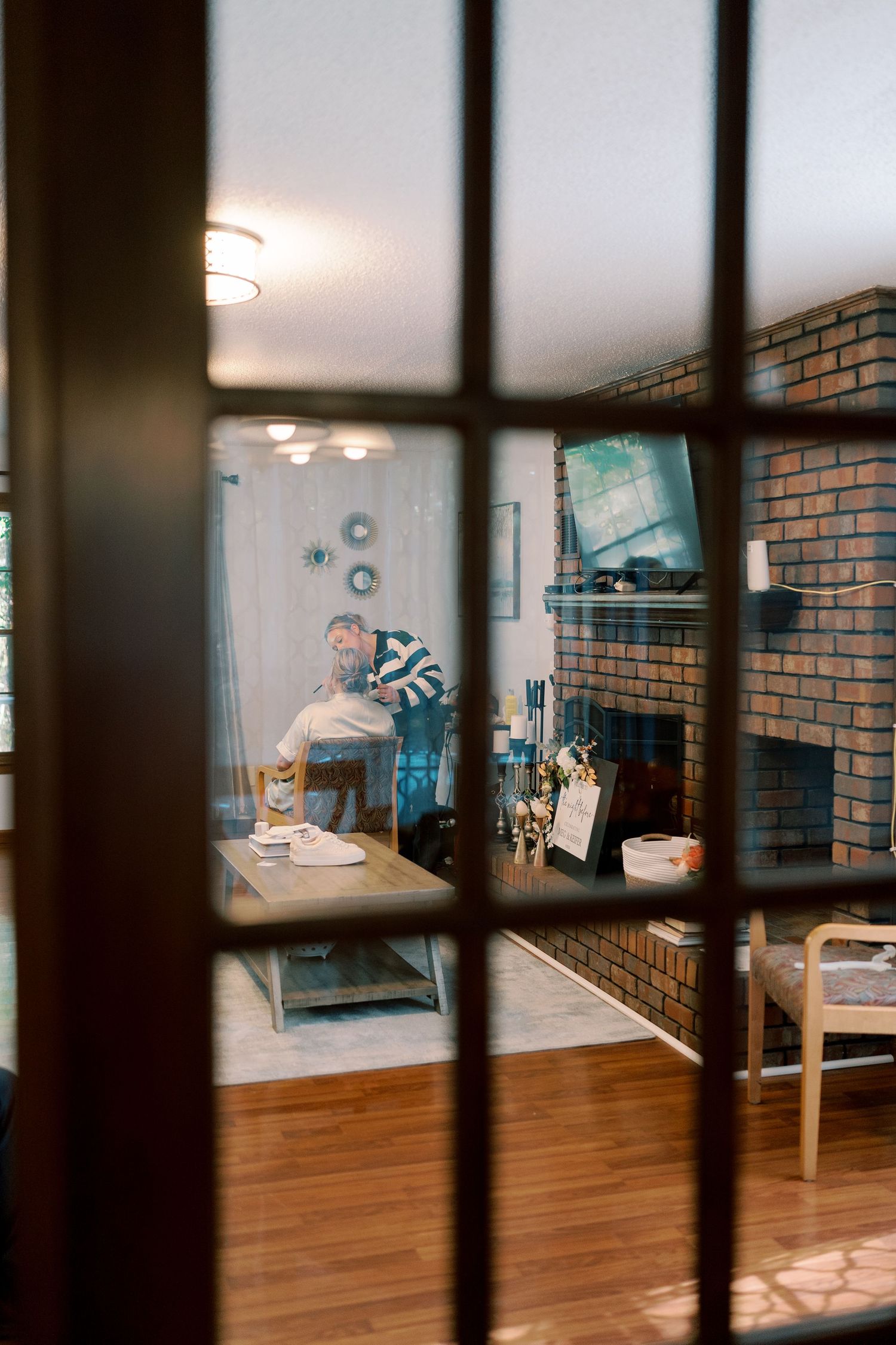 Interior view of a room with brick walls and hardwood floors seen through window panes.