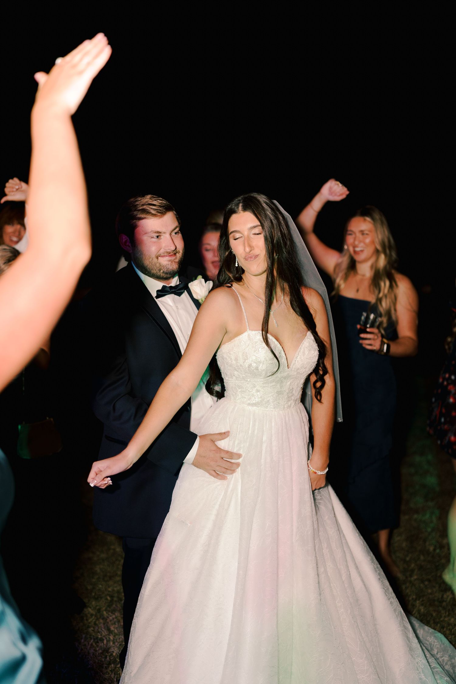 Wedding party dancing and celebrating during an evening outdoor reception.